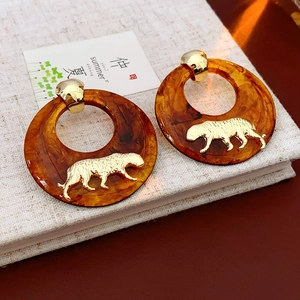 Close-up of resin amber hoop earrings with gold leopard relief on a textured notebook