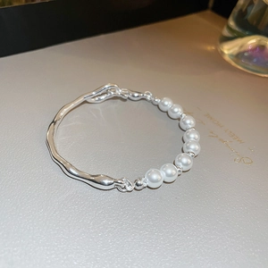 Macro detail of freshwater pearls and irregular silver-tone metal links on a stylish bracelet