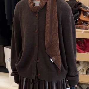 Detail of a brown silk scarf necklace with paisley patterns on a knit cardigan