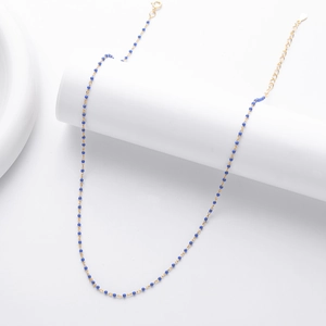 Close-up of gold chain necklace with blue beads on a white minimalist pedestal stand