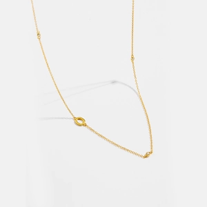 Detail view of gold letter necklace with bezel-set cubic zirconia and hollow ring elements