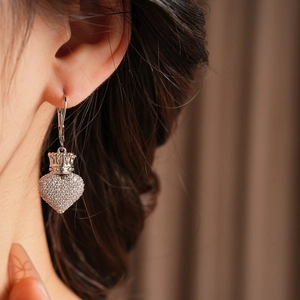 Détail macro de boucles d'oreilles cœur argenté avec couronne et zircons brillants
