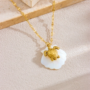 18K gold plated stainless steel necklace with turtle and sea shell charms on stone background