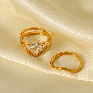 Golden titanium steel four-leaf clover ring set with zircon stones on champagne satin fabric