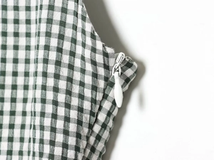 Détail du zip invisible sur une robe mi-longue à carreaux verts et blancs