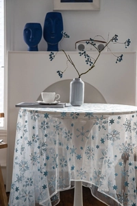 Detail of white transparent tablecloth featuring blue and silver snowflake embroidery