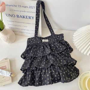 Detail einer schwarzen Stofftasche mit Rüschen und gelben Blumenmustern im Set