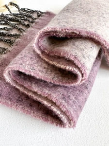 Detailed close-up of pink and beige blended wool-like scarf with grey fringe tassels