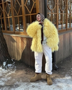 Close-up of yellow faux fur coat texture with plush fluffy fibers for winter warmth
