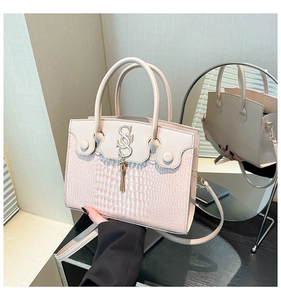 Detail view of pink crocodile pattern handbag with SS logo and tassel via mirror reflection