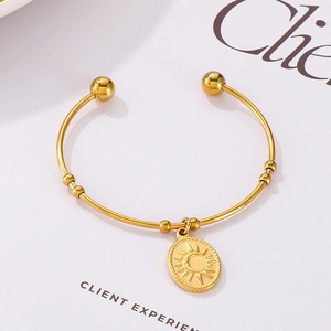 Détail du pendentif ovale gravé soleil et lune sur un bracelet jonc en acier inoxydable