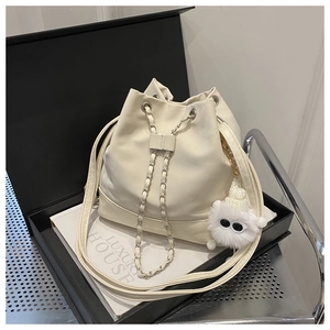 Detail of off-white PU leather bucket bag with chain strap and plush pendant decoration