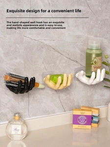 Detail showing hand-shaped wall hooks holding a comb and soap on a marble wall
