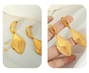 Detailed view of gold plated leaf shaped earrings with textured metal finish and earnuts