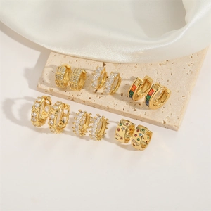 Set of six gold-plated vintage hoop earrings with zircons on a light stone surface