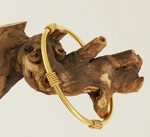 Detailed macro shot of an 18K gold-plated stainless steel chain cuff on a driftwood display