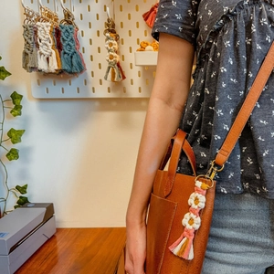 Porte-clés marguerite en macramé fait main avec pompons sur un sac en cuir brun