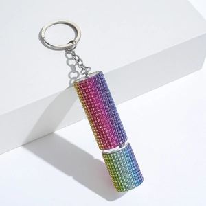 Detailed shot of rainbow rhinestone perfume bottle keychain on a white geometric stand