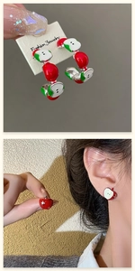 Detail of red apple asymmetric earrings with crystal accents on a model and card