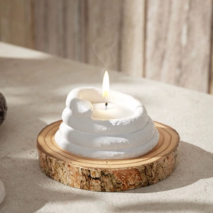 Artistic white spiral candle holder on a wooden base with natural sunlight and shadows