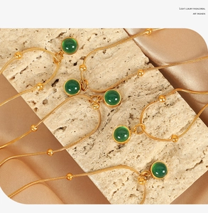 Close-up of gold plated snake bone necklaces with vintage green stone pendants on silk