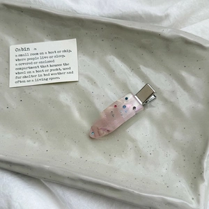 Detailed macro view of a translucent pink resin hair clip with colorful rhinestones