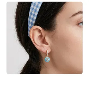 Elegant heart-shaped zircon earrings with light blue enamel finish on female model