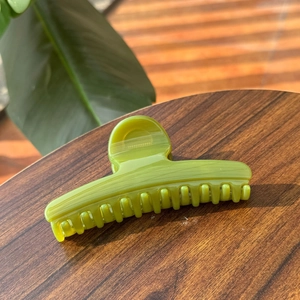 Detail of a translucent green butterfly hair claw clip on a dark wooden table background