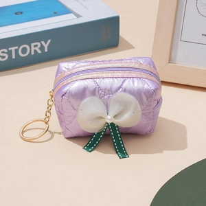 Detail of purple quilted mini pouch with satin bow, pearl charm, and gold keychain