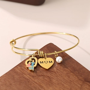 Detail of MOM heart charm and pearl on golden stainless steel adjustable bracelet