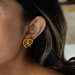 Gros plan d'une boucle d'oreille cœur en acier inoxydable doré 18 carats sur un modèle