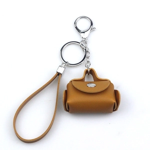 Detail of a brown leather mini bag perfume bottle keychain with silver hardware and wrist strap