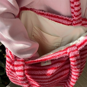 Close-up of plush striped tote bag interior showing beige lining and zipper pocket