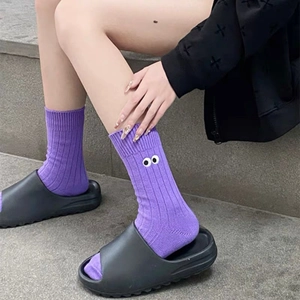 Close-up of purple slouch socks with embroidered cartoon eyes and ribbed cuff texture