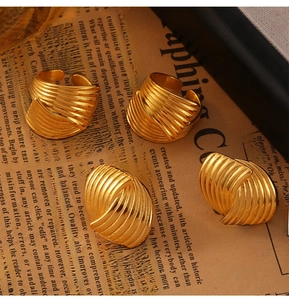 Flat lay of 18K gold plated jewelry set with textured earrings and rings on newspaper