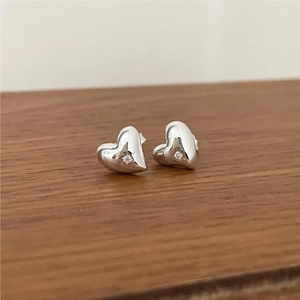 Close-up of S925 sterling silver heart stud earrings with sparkling clear zircon on wood