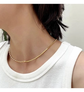 Close-up of gold-plated half snake chain and zircon pavé link necklace on model