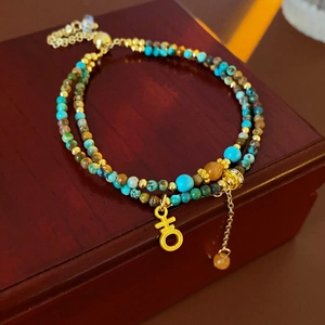 Détail du bracelet double rangée avec perles turquoise et breloques en métal doré