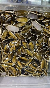 Close-up of bulk tiger eye faceted oval pendants with gold plated edges for jewelry making