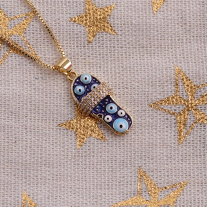 Gros plan d'un collier doré avec pendentif pantoufle œil bleu sur tissu étoilé