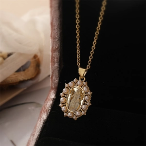 Close-up of gold-plated Virgin Mary pendant with white pearl border on a black velvet box