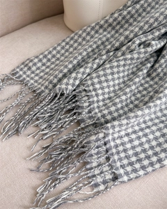 Detailed close-up of grey and white houndstooth scarf texture with soft fringe edges