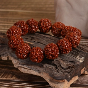 Deep reddish-brown natural Rudraksha seed bracelet placed on an antique wood base