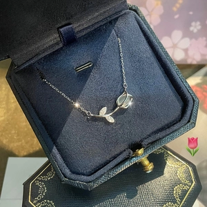 Macro shot of silver tulip necklace with opal and zircons in a navy velvet jewelry box