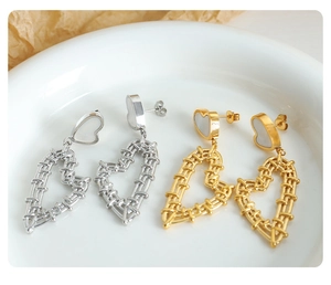 Detail of gold and silver heart earrings with woven texture and shell inlay