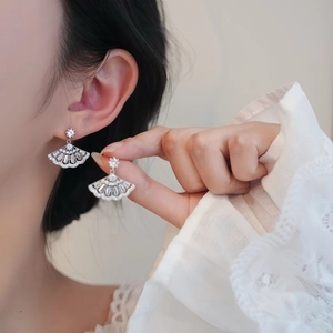 Macro shot of silver fan-shaped earrings with sparkling cubic zirconia on model
