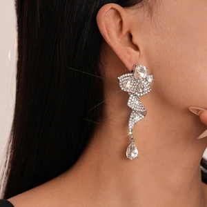 Close-up of elegant silver ribbon drop earrings with pear-shaped cubic zirconia on model