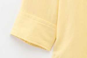 Detail of light yellow shirt sleeve showing premium linen texture and neat stitching