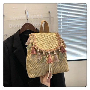 Macro detail of straw bucket bag featuring colorful fringe tassels and woven texture
