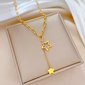 Macro shot of gold paperclip chain necklace featuring double star tassels on silk backdrop